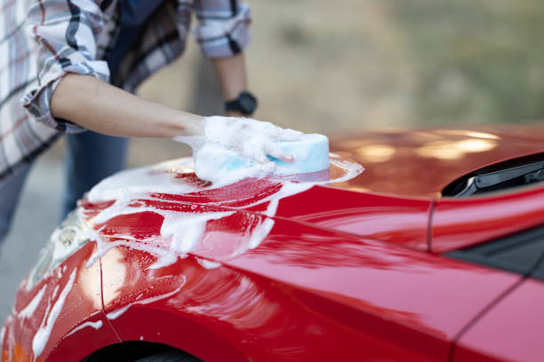 istock Young handsome man having a good time while washing his car in the forest 2183295562