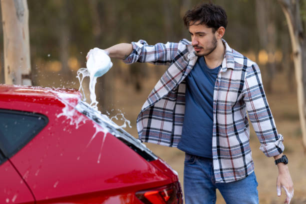 istock Young handsome man having a good time while washing his car in the forest 2183295610