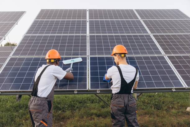 Hướng dẫn vệ sinh pin mặt trời an toàn tại nhà 10 Technicians Cleaning Large Solar Panels Outdoors with Brushes Two technicians in protective gear clean large solar panels with brushes outdoors. The image emphasizes renewable energy maintenance and environmental sustainability efforts. Safe Step-by-Step Solar Cleaning Process stock pictures, royalty-free photos & images
