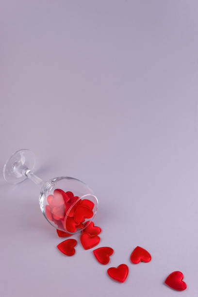 red hearts in a wine glass minimalism on a plain background.