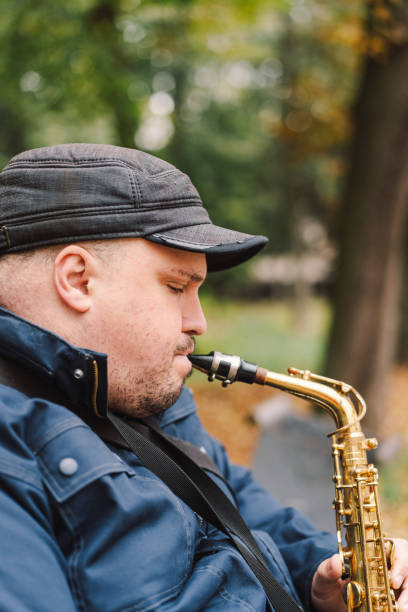 istock A saxophonist performs in a serene park during autumn while seated on a bench 2183298470