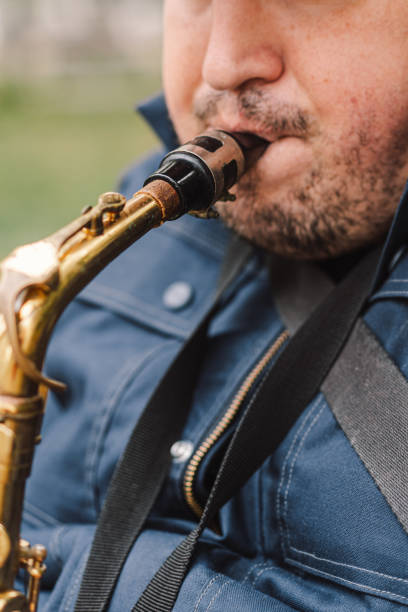 istock A saxophonist performs in a serene park during autumn while seated on a bench 2183298515