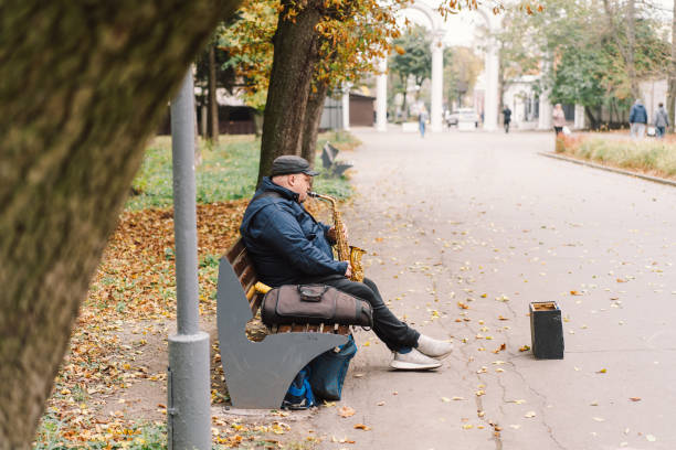 istock A saxophonist performs in a serene park during autumn while seated on a bench 2183298643