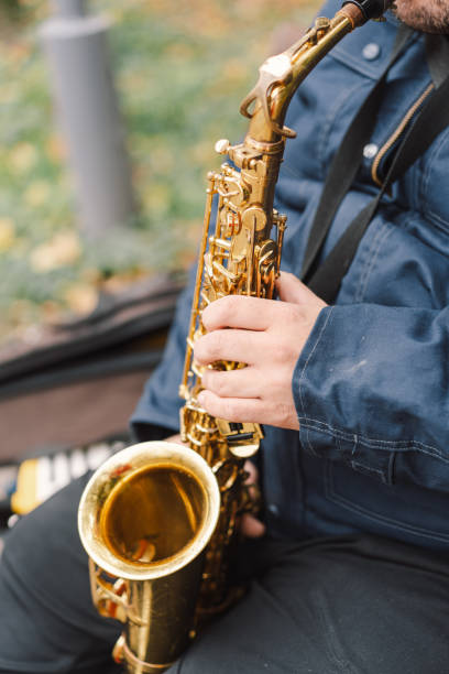 istock A saxophonist performs in a serene park during autumn while seated on a bench 2183298652