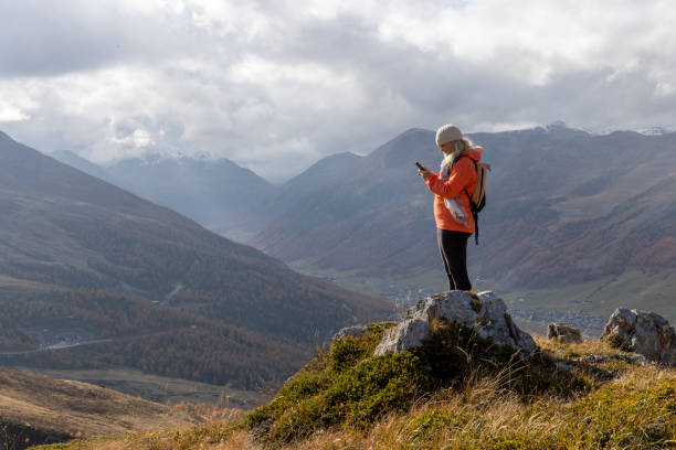 istock Mature woman uses mobile phone on mountain top 2183301296