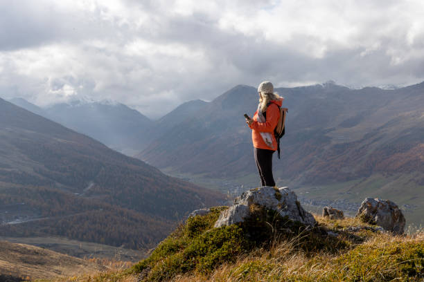 istock Mature woman uses mobile phone on mountain top 2183301301