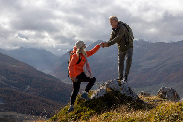 istock Mature couple give helping hand onto mountain top 2183301352