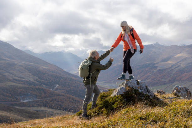 istock Mature couple give helping hand onto mountain top 2183301378