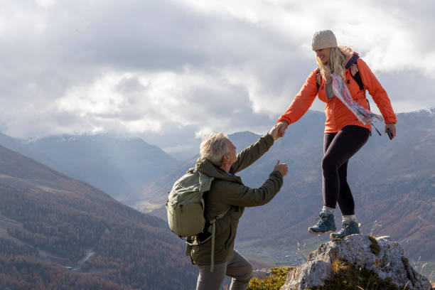 istock Mature couple give helping hand onto mountain top 2183301410