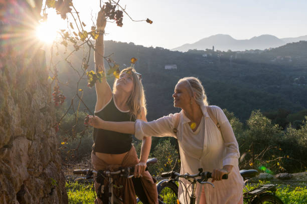Mother and adult daughter pick grapes in countryside
