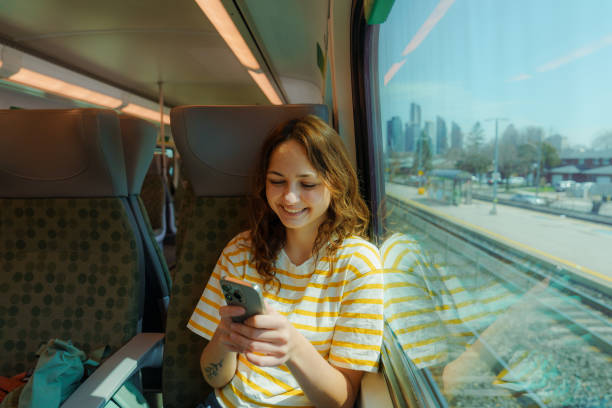 istock Woman using smartphone and looking through the window traveling by train in Canada 2183305882
