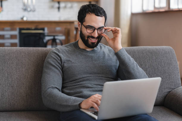 istock Happy arabian man in eyeglasses sitting at home relaxing using laptop 2183306836
