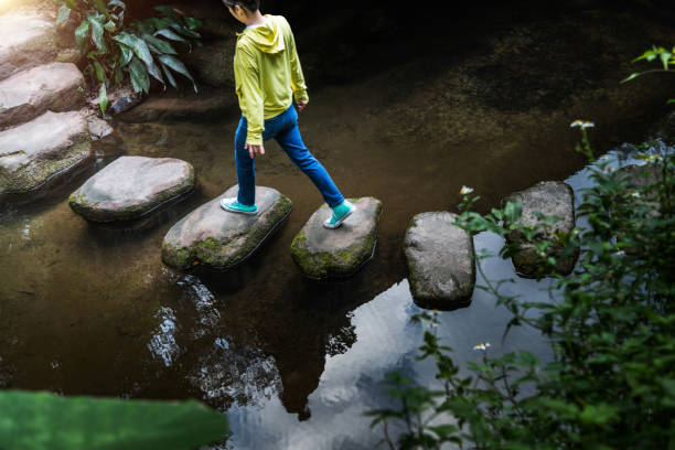 istock Woman walking on stepping stones 2183306924