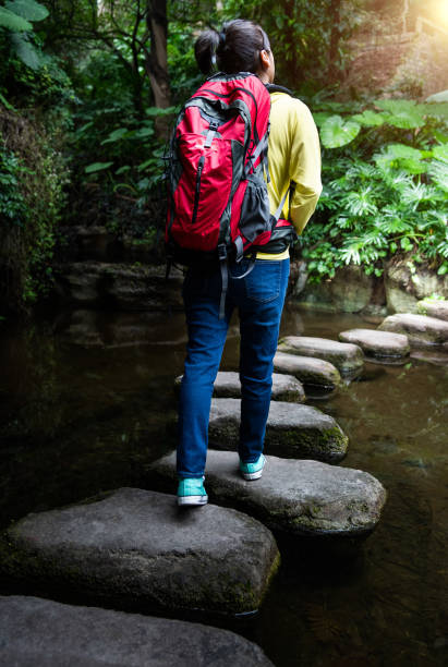istock Female backpacker walking on stepping stones 2183306927