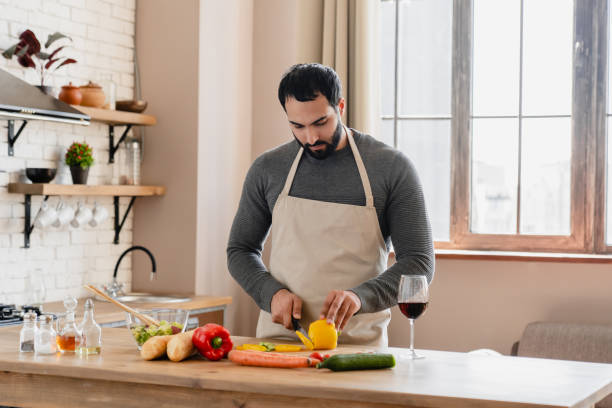 istock Happy Arabian man preparing dinner in kitchen slicing vegetables at table with fresh ingredients 2183307374