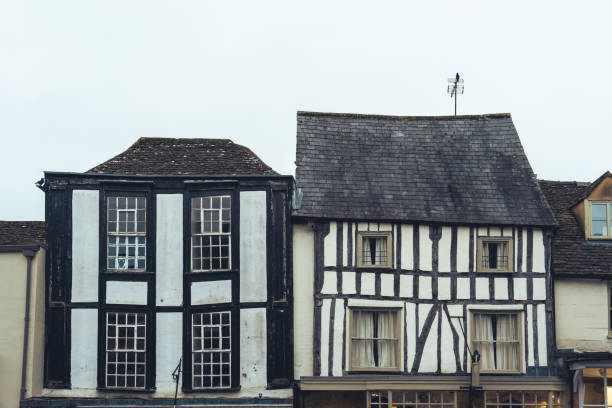Rye, UK-June 2, 2024; Close up of part of the façade of a Tudor style building with roses and flowers growing in front on cobbled Church Square