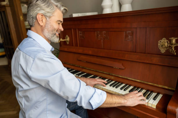 istock Gray-haired mature man playing the piano and looking involved 2183310110