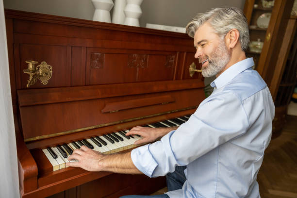 istock Gray-haired mature man playing the piano and looking involved 2183310113