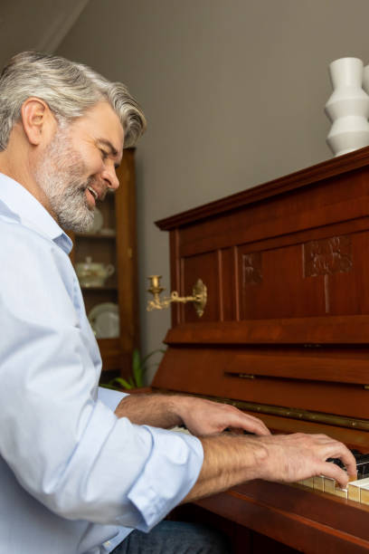 istock Gray-haired mature man playing the piano and looking involved 2183310127