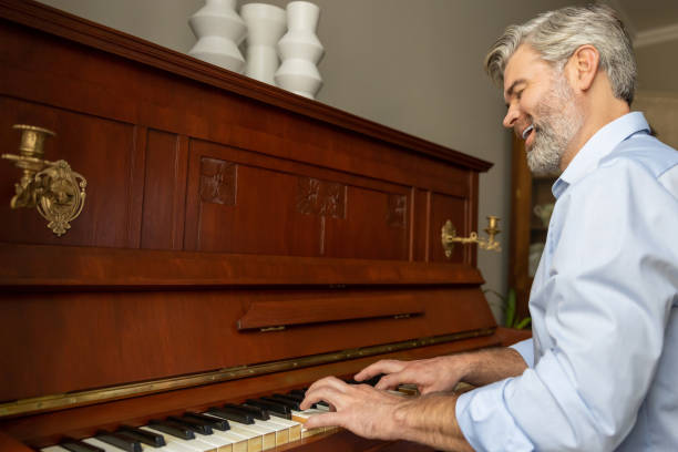 istock Gray-haired mature man playing the piano and looking involved 2183310134
