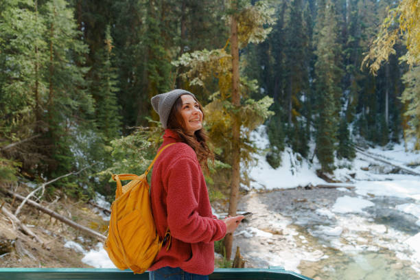 Woman using smartphone hiking in the forest in Johnston Canyon, Canada