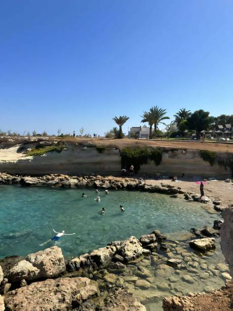 istock Scenic rocky beach with swimmers and palm trees. 2183319864
