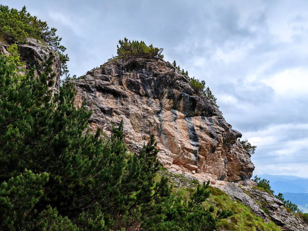 istock Scenic view of a rocky mountain formation with greenery under a cloudy sky 2183323752