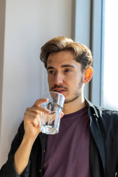 istock Handsome young man drinking water from a water glass 2183325920