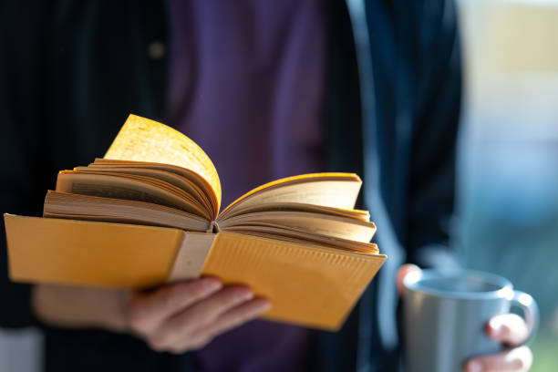 istock Close-up of unknown man reading book while drinking coffee 2183326145