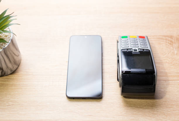 istock Smartphone and pos terminal lying on wooden table for contactless payment 2183334555