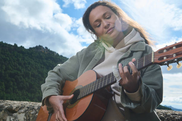 istock Woman playing guitar outdoors with mountain backdrop 2183336044