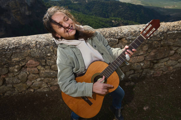 istock Woman playing acoustic guitar outdoors with a joyful expression 2183336056
