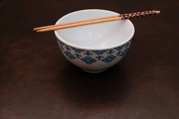 istock White bowl with blue pattern outside and wooden chopsticks on brown background 2183338151