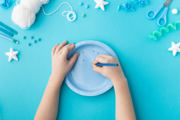 Snowflake made from wool threads on blue paper plate Christmas ideas for kindergarten diy stock photo