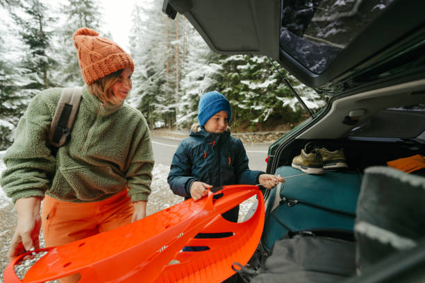 man and woman dressing into ski equipment near suv car. mountains on background