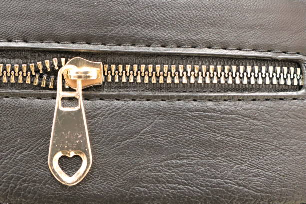 This is a detailed closeup view of a stylish zipper featuring a heartshaped pull on a sleek black leather surface