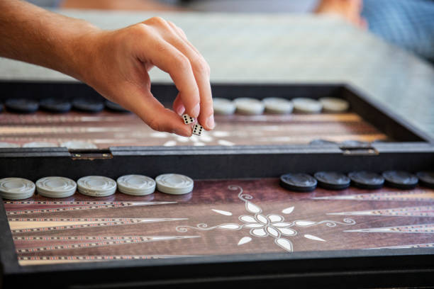 istock Hand rolling dice in traditional backgammon game close-up 2183346244