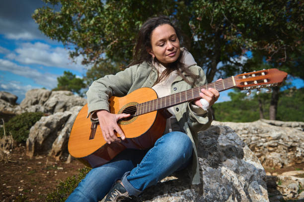 istock Woman playing guitar outdoors on a sunny day 2183352177