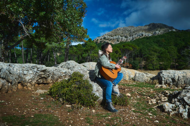 istock Woman playing guitar in peaceful mountain landscape 2183352179