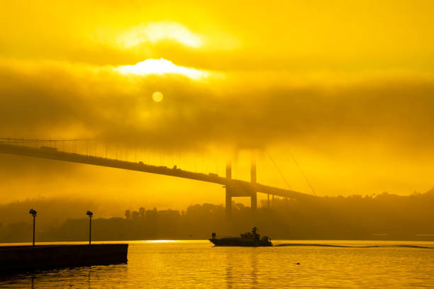 A boat moves through the fog on the Bosphorus. The 15 July Martyrs Bridge and Ortaköy Mosque in a fog.