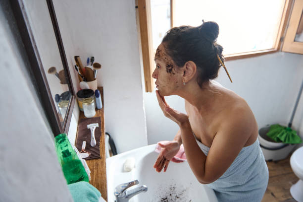 istock Woman applying coffee face scrub in cozy bathroom setting 2183356098