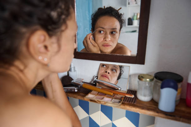 istock Woman reflects deeply in the bathroom mirror, applying makeup 2183356170