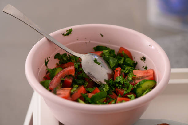 A colorful bowl filled with chopped tomatoes, cucumbers, and herbs awaits a delightful meal in a sunny kitchen.