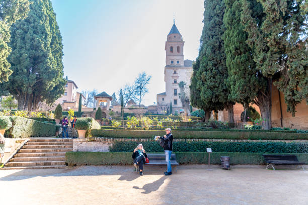 Granada, Granada - Spain - 01-30-2024: Visitors near the Santa Maria de la Encarnacion Church amidst the Alhambra gardens, with its towering bell tower