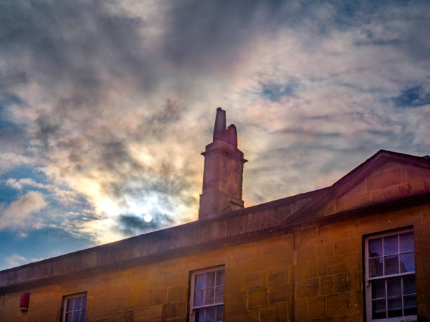 The sun shines through the clouds above the ancient buildings