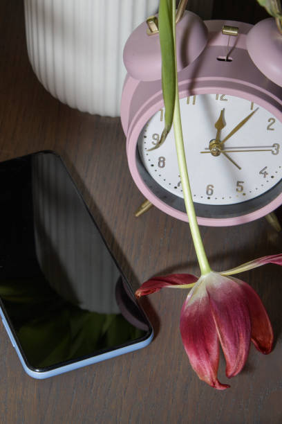 istock Silent smartphone on the table, watch with withered tulips close-up 2183371657