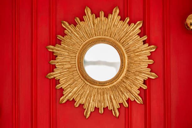 Golden sunburst mirror on vibrant red wall adds charm to interior space