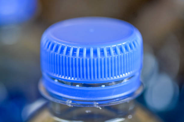 The image focuses on a blue plastic bottle cap, highlighting its circular shape and textured surface.