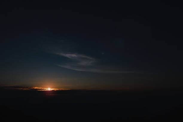 A dramatic silhouette of an individual standing on a hilltop, gazing at a vibrant sunrise over the horizon. The warm colors of the morning sky contrast with the dark outline of the figure, evoking feelings of peace, hope, and new beginnings. Perfect for inspirational, wellness, or outdoor themes.