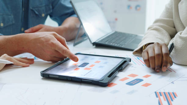 istock Close up Diverse Collaborative Business people meeting with Digital Devices computer brainstorming the financial report paperwork document analyzing data or planning strategies displays a graph or chart in a modern business technology 2183385381